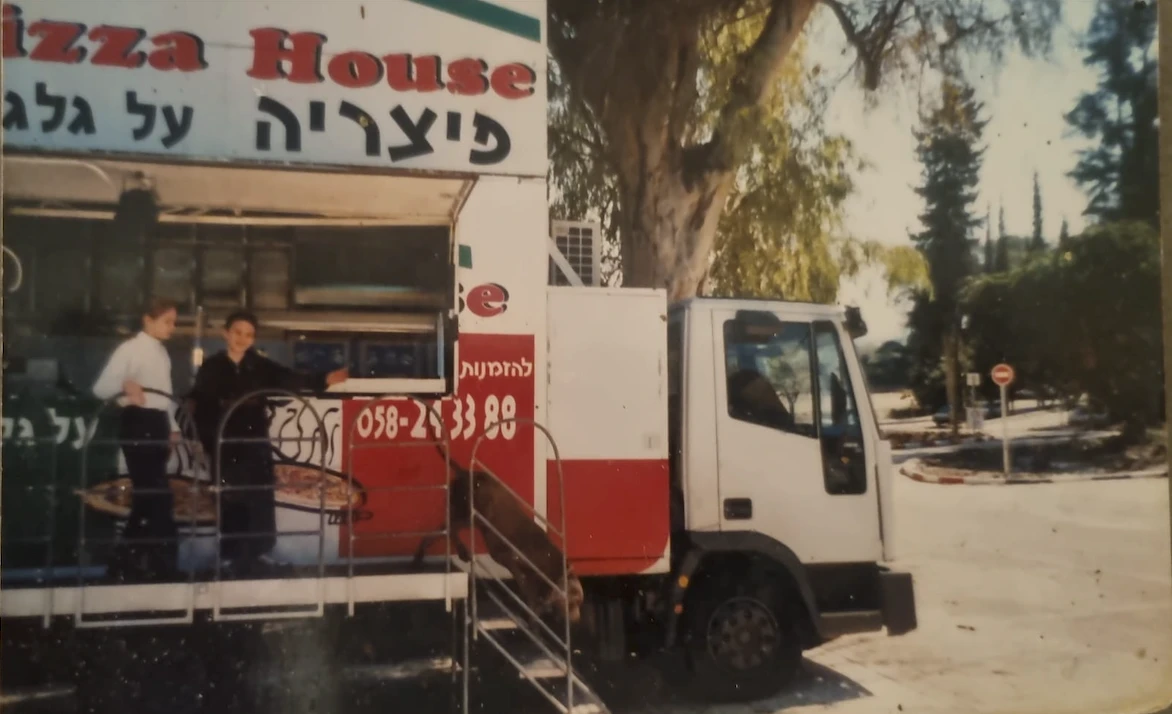 הפוד טראק של פיצה פי 2 בשנות ה-90 — משאית פיצה עם חלון הגשה, מגשי פיצה על הדלפק ושלט 'פיצריה על גלגלים'